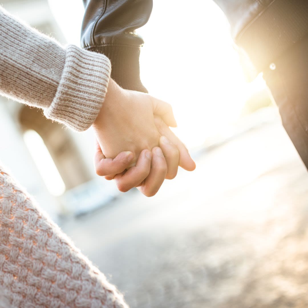Jong koppel dat hand in hand in het zonlicht wandelt.