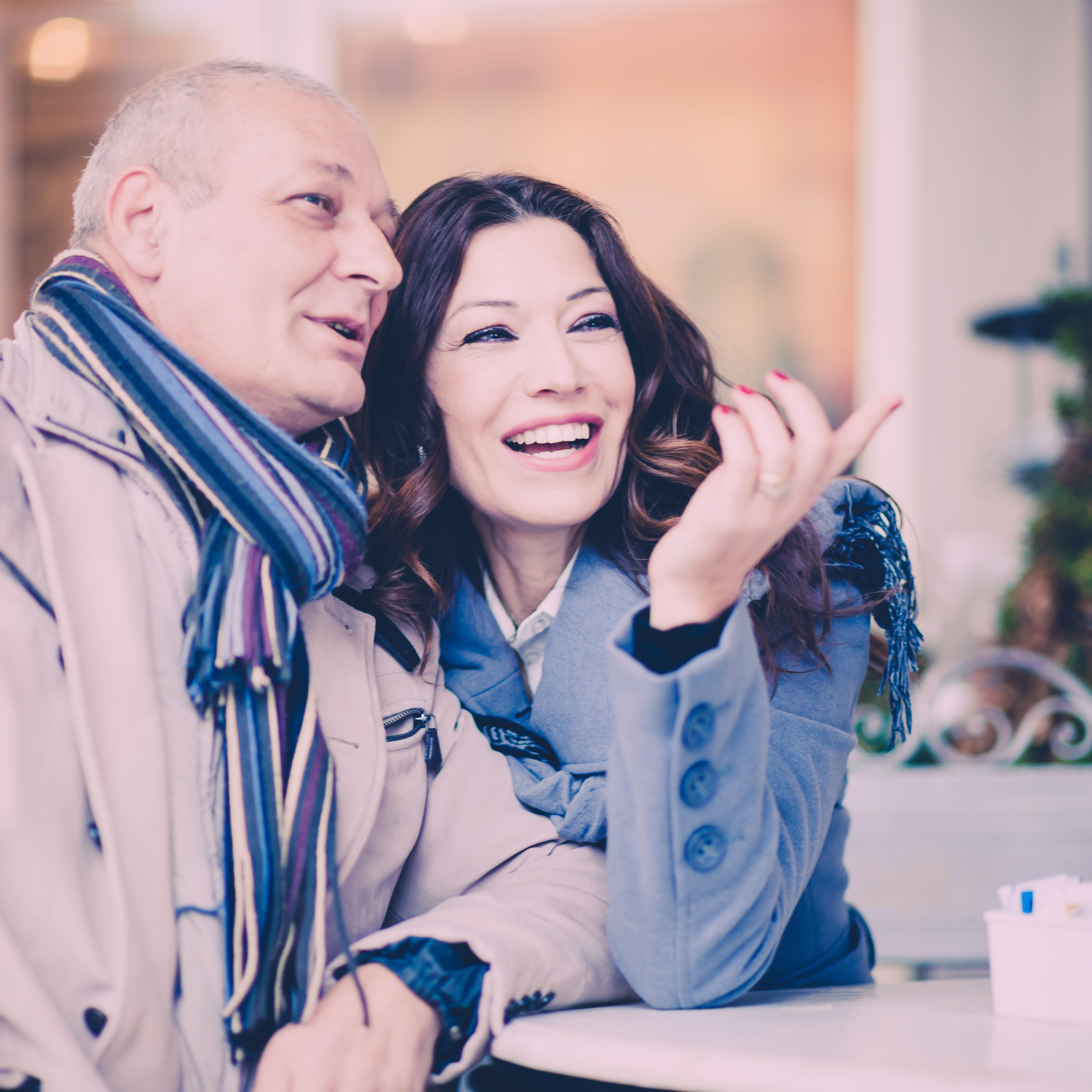 Man en vrouw van rond de 50 die glimlachend met elkaar praten tijdens een ontmoeting.